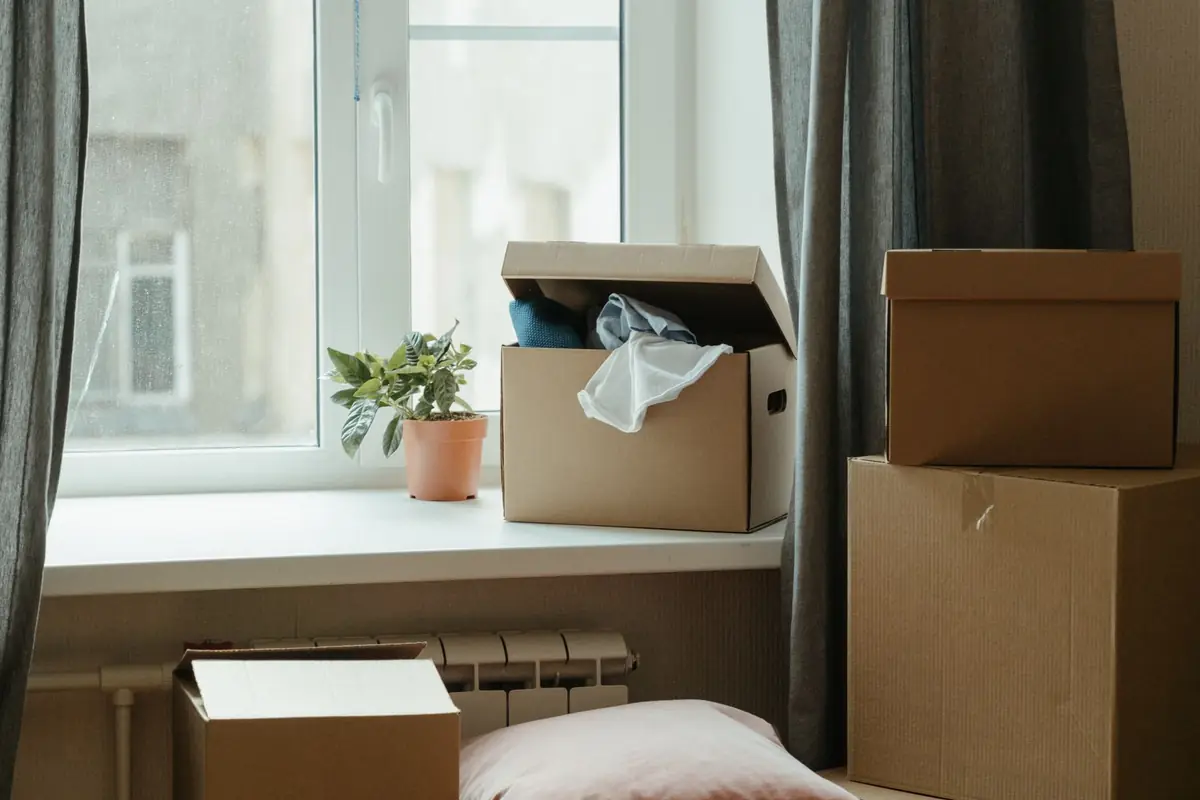 Moving boxes stacked by a window in an emptied room on move-out day