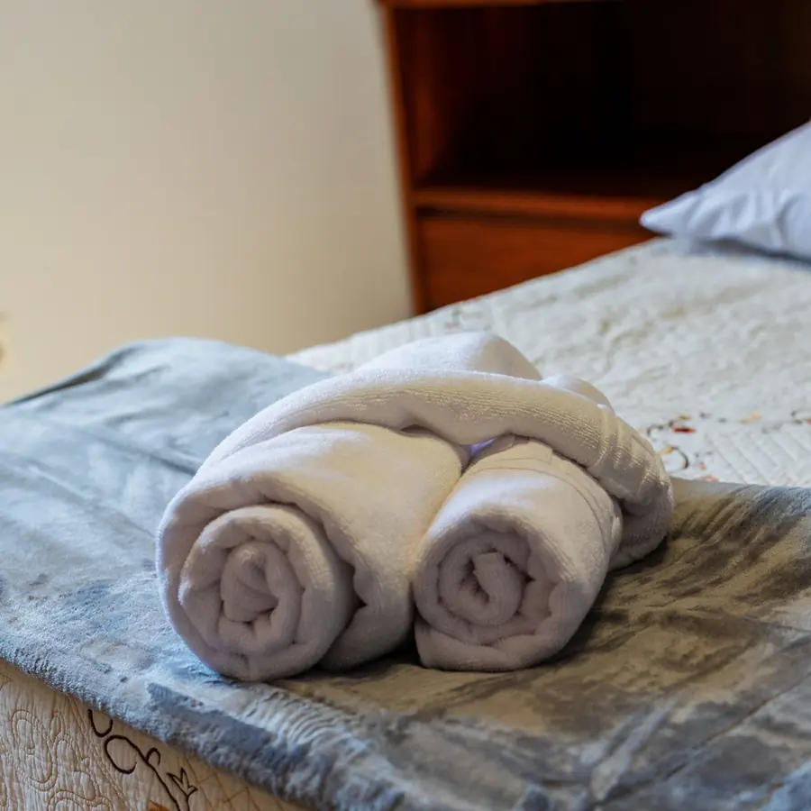 Rolled guest towels on a freshly made bed in a vacation rental after an Airbnb turnover